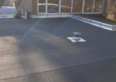 Toiture plate recouverte d'une étanchéité bitumeuse, avec chapeau de ventilation et relevés en zinc