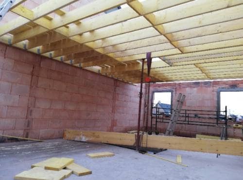 Intérieur d'une maison neuve en brique, charpente et solivage en bois posés, panneaux d'isolant au sol