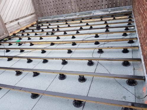 Lambourdes posées sur plots réglables au-dessus de l'étanchéité d'un toit plat, avant la pose du platelage