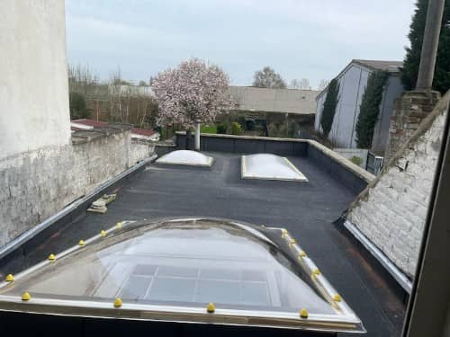 Toit-terrasse étanché en bitume avec trois dômes transparents, dont un grand au premier plan